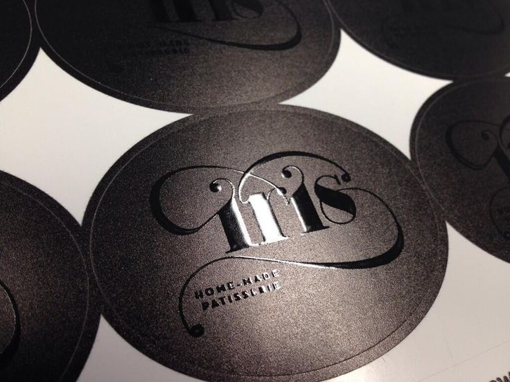 Stiker bulat hitam dengan logo Iris Home-Made Patisserie sebagai contoh elemen branding pada kemasan unboxing.