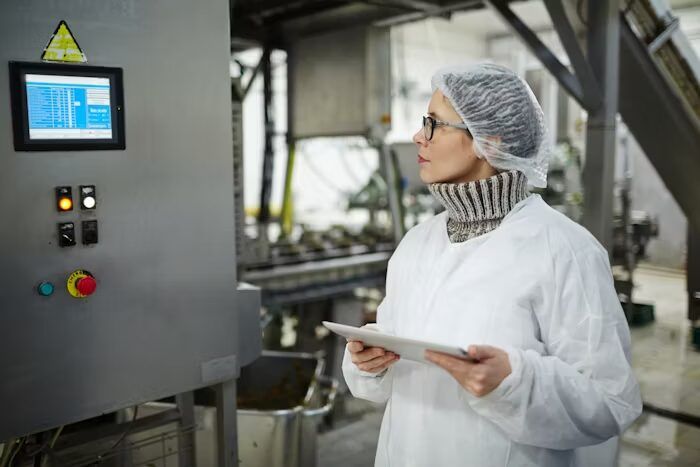 Pekerja memeriksa alat kontrol di pabrik dengan tablet.