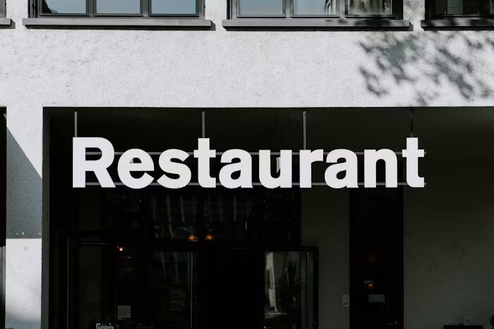 Tanda restoran besar di depan bangunan putih yang menunjukkan pentingnya identitas visual usaha kuliner