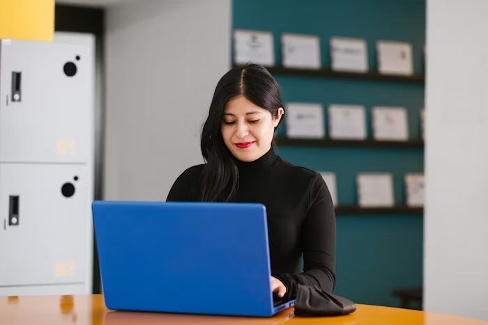 Perempuan sedang menggunakan laptop di ruang kerja modern.