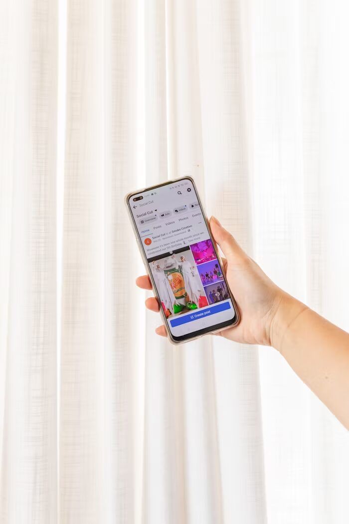 Tangan memegang smartphone menampilkan aplikasi percetakan online