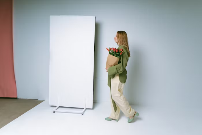 Perempuan memegang karangan bunga di studio dengan background minimalis.