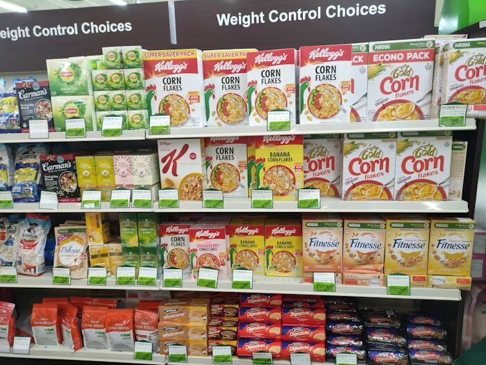 Rak toko dengan berbagai jenis makanan Kellogg's dan Carman's di bagian kontrol berat badan.