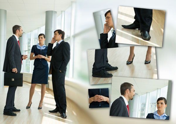 Tiga orang dalam pakaian kerja berbicara di ruang kantor modern.