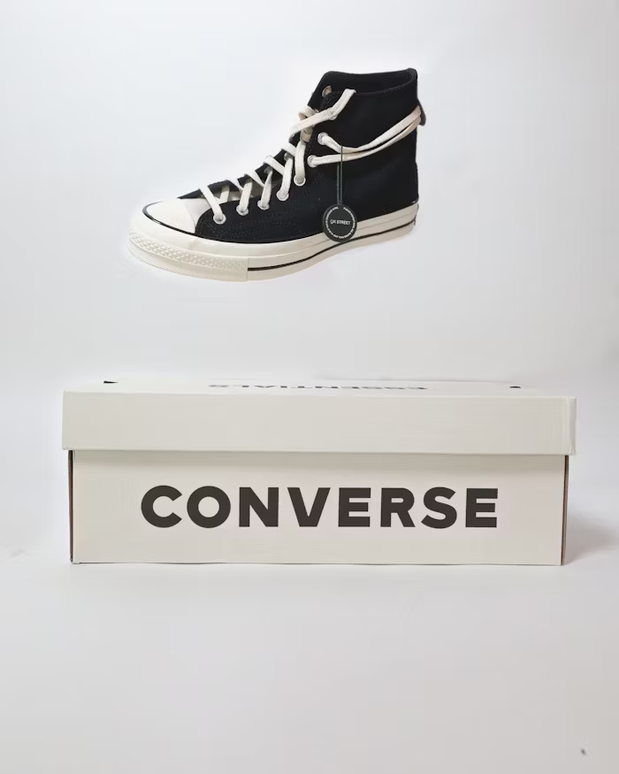 Sepatu Converse hitam tinggi dengan kotak sepatu berlabel 'Converse' di depan.