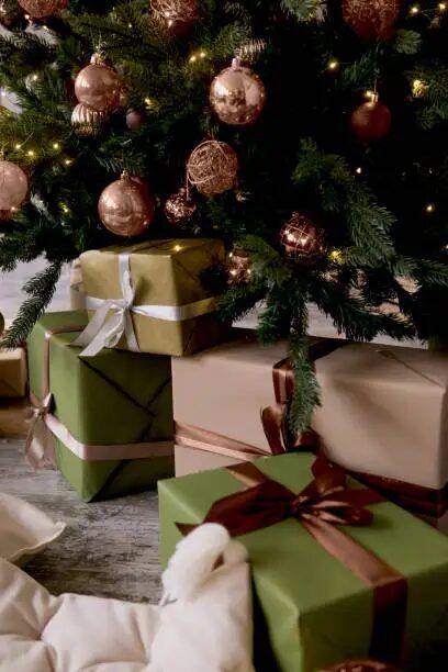 Pohon Natal berhias dengan hadiah-hadiah berwarna hijau dan emas di bawahnya.