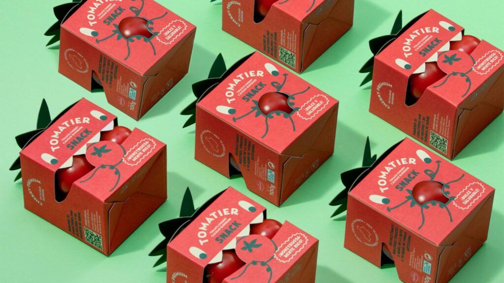 Paket snack tomat merah dalam kotak merah dengan label 'Tomatier Snack' di latar hijau.