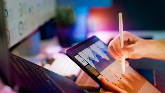 Tangan menggunakan stylus pada tablet untuk analisis data visual.