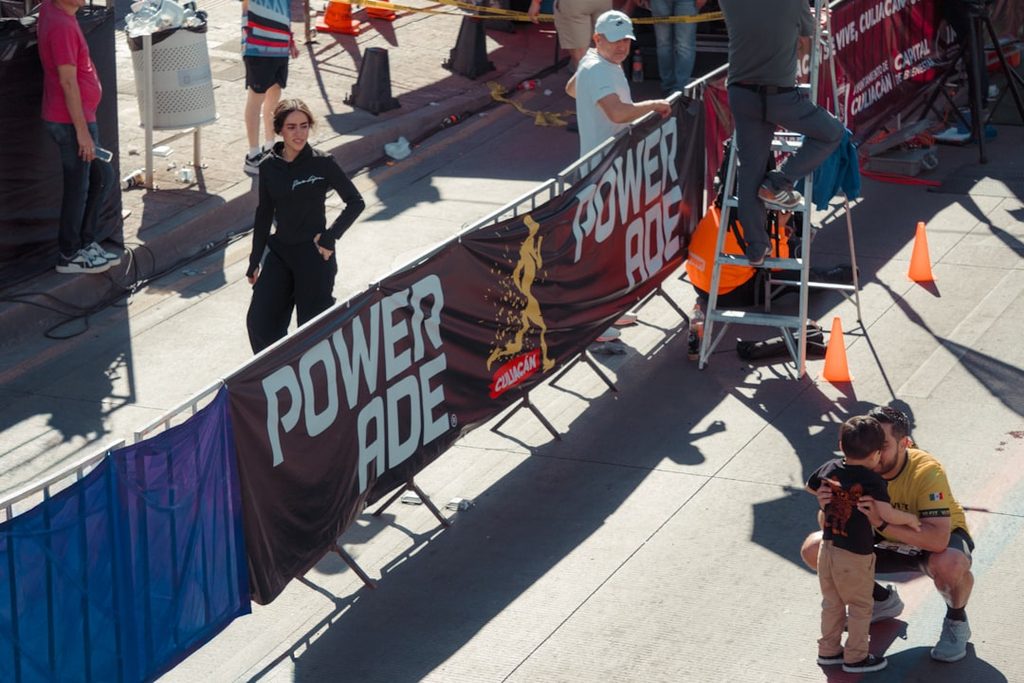 Banner Powerade di event olahraga, orang berpose dan berinteraksi.
