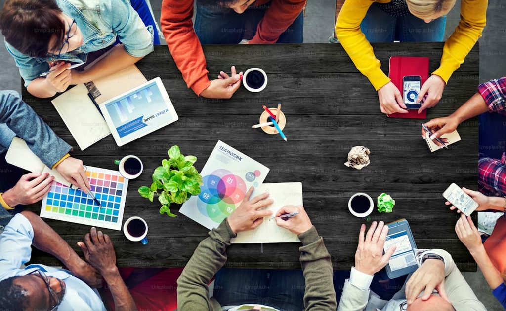 Grup orang sedang bekerja sama dalam proses desain grafis dan manajemen aset visual untuk materi promosi brand.