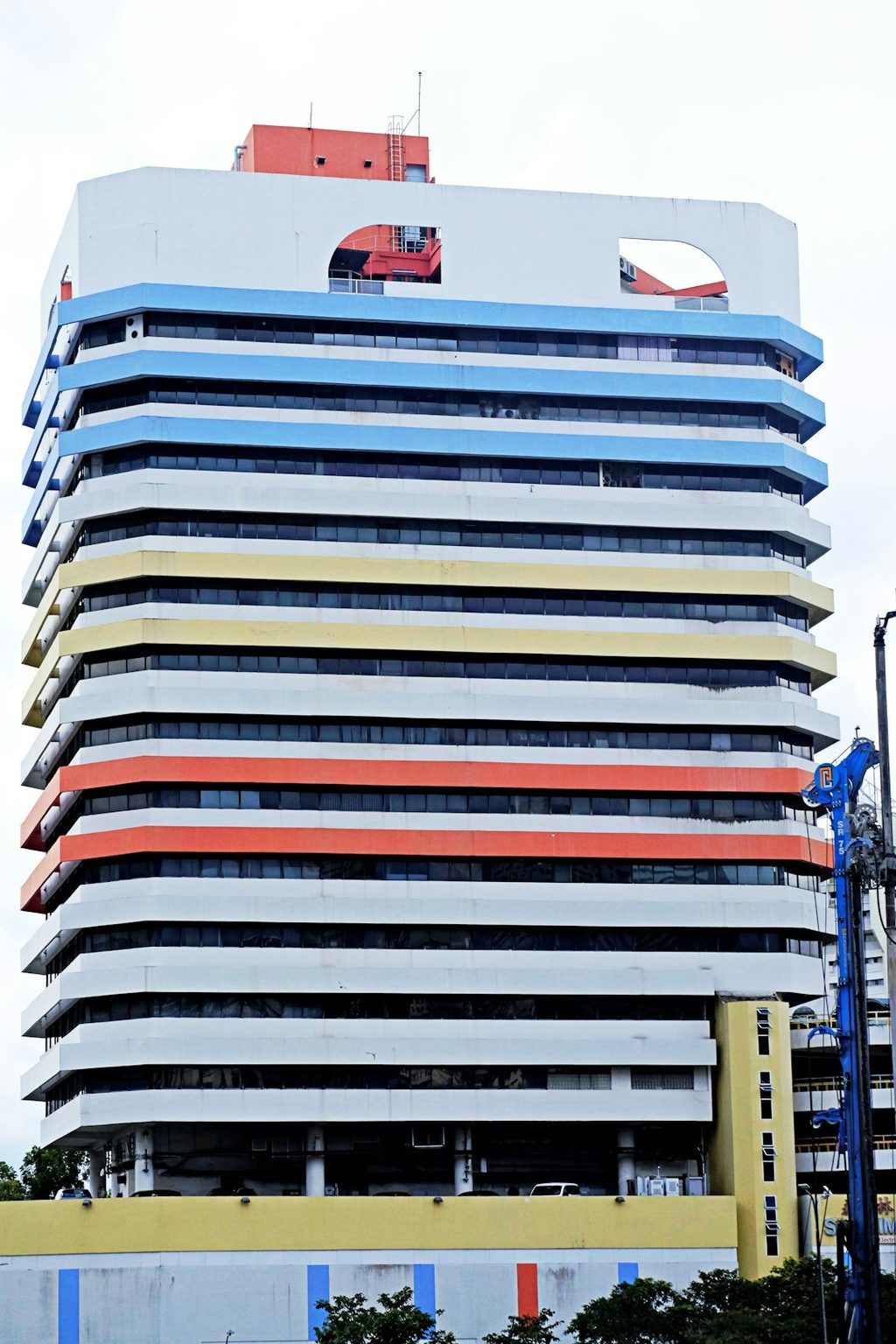 Gedung tinggi dengan lantai berwarna cerah dan detail unik pada atap.