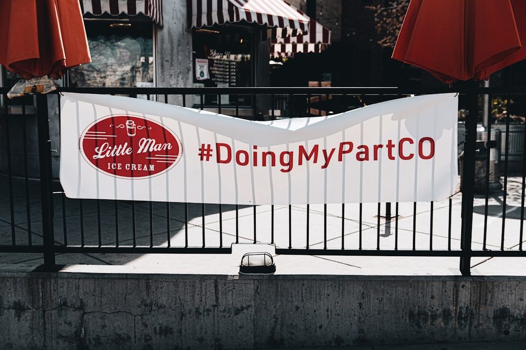 Banner event dengan hashtag di area masuk yang mudah terbaca dan mendorong pengunjung berfoto.