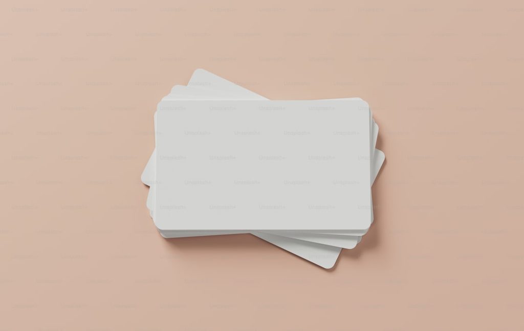 Stack of white business cards on a beige background.