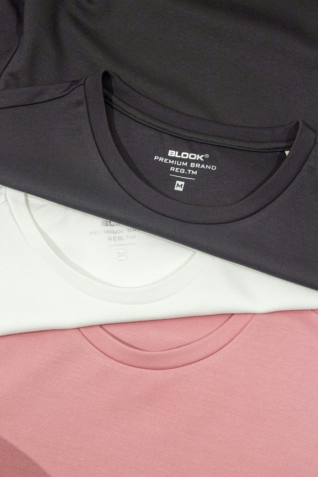 Tiga t-shirt warna putih, hitam, dan pink dengan logo Blox Premium Brand.