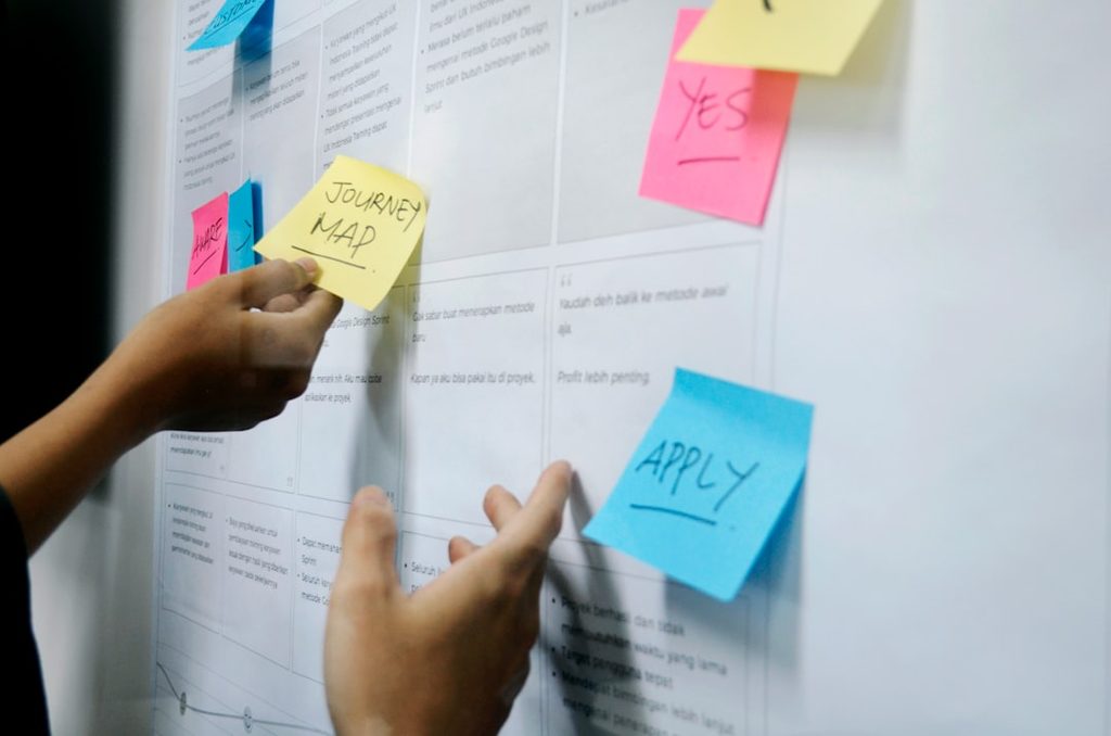 person holding yellow sticky notes while planning awareness messaging