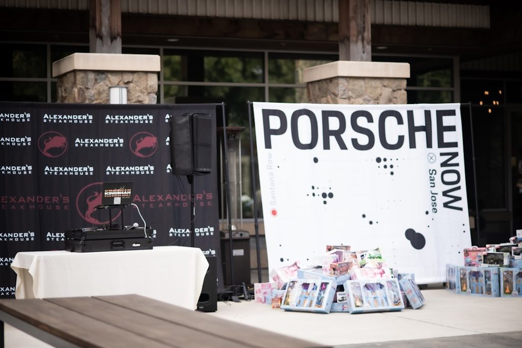 Display Porsche di acara dengan banner dan stand promosi yang menata elemen visual di sisi area foto.