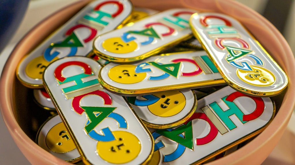 Banyak pin dengan logo Chicago dan wajah kartun di dalam wadah.