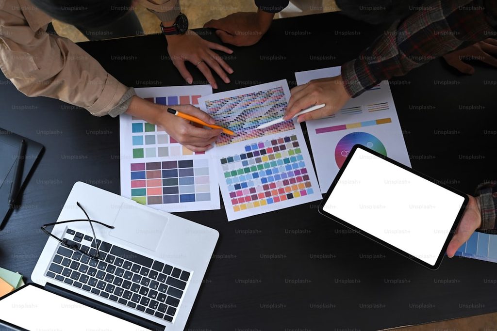 Tim desainer memilih sampel warna CMYK dan gramatur kertas menggunakan tablet digital