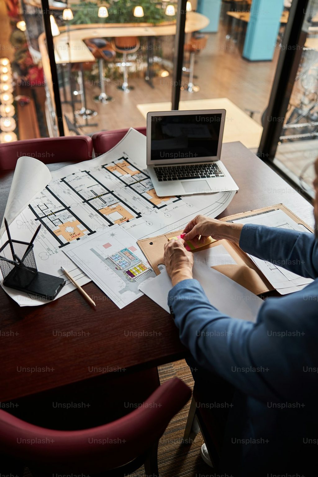 Desainer arsitektur sedang menggambar rancangan rumah di kafe modern.