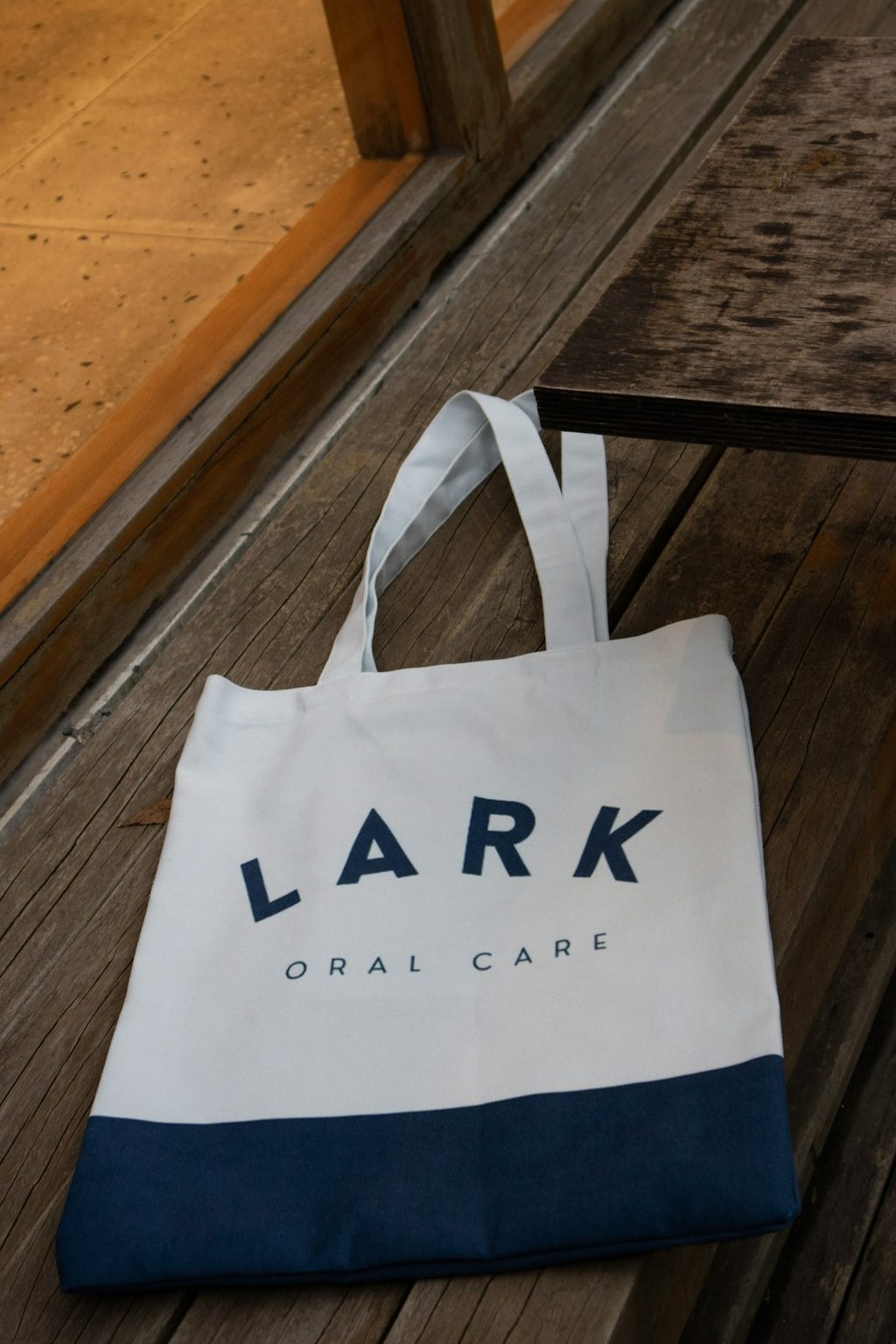Tas putih dengan tulisan 'LARK ORAL CARE' di bagian depan, dihiasi warna biru pada bagian dasar.