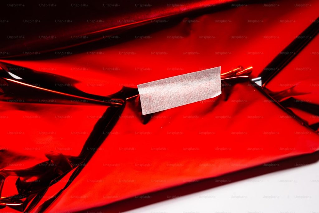Red envelope with a silver sticker on it, suitable for packaging or mailing.