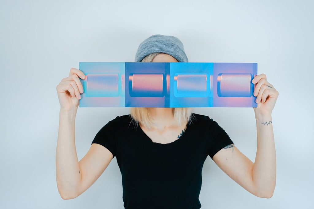 Perempuan menunjukkan contoh cetakan biru dan ungu dari aplikasi Uprint.id