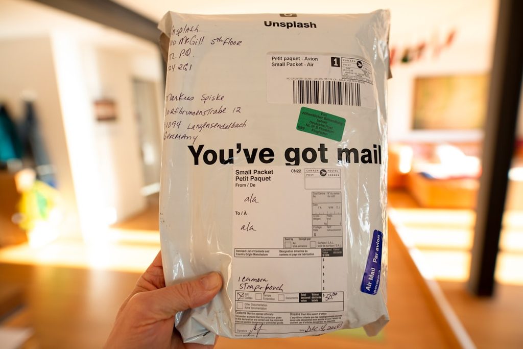 Tangan memegang kemasan pengiriman dengan tulisan You've got mail sebagai contoh kemasan yang mengundang interaksi konsumen.