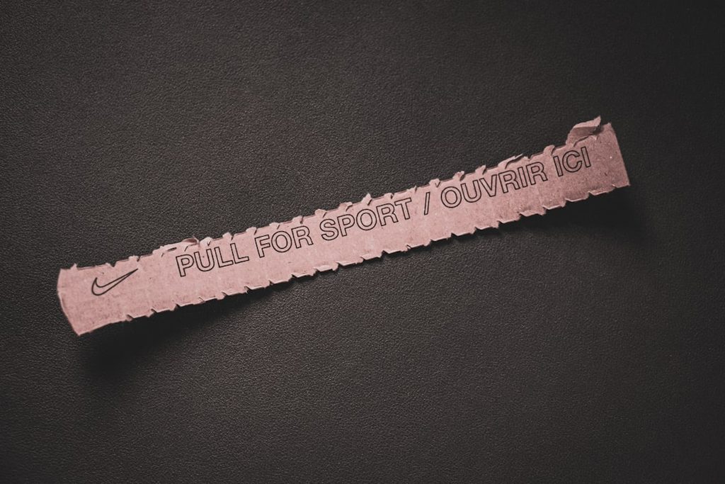 Label stiker Nike dengan teks PULL FOR SPORT OUVRIR ICI sebagai contoh detail potong dan finishing.