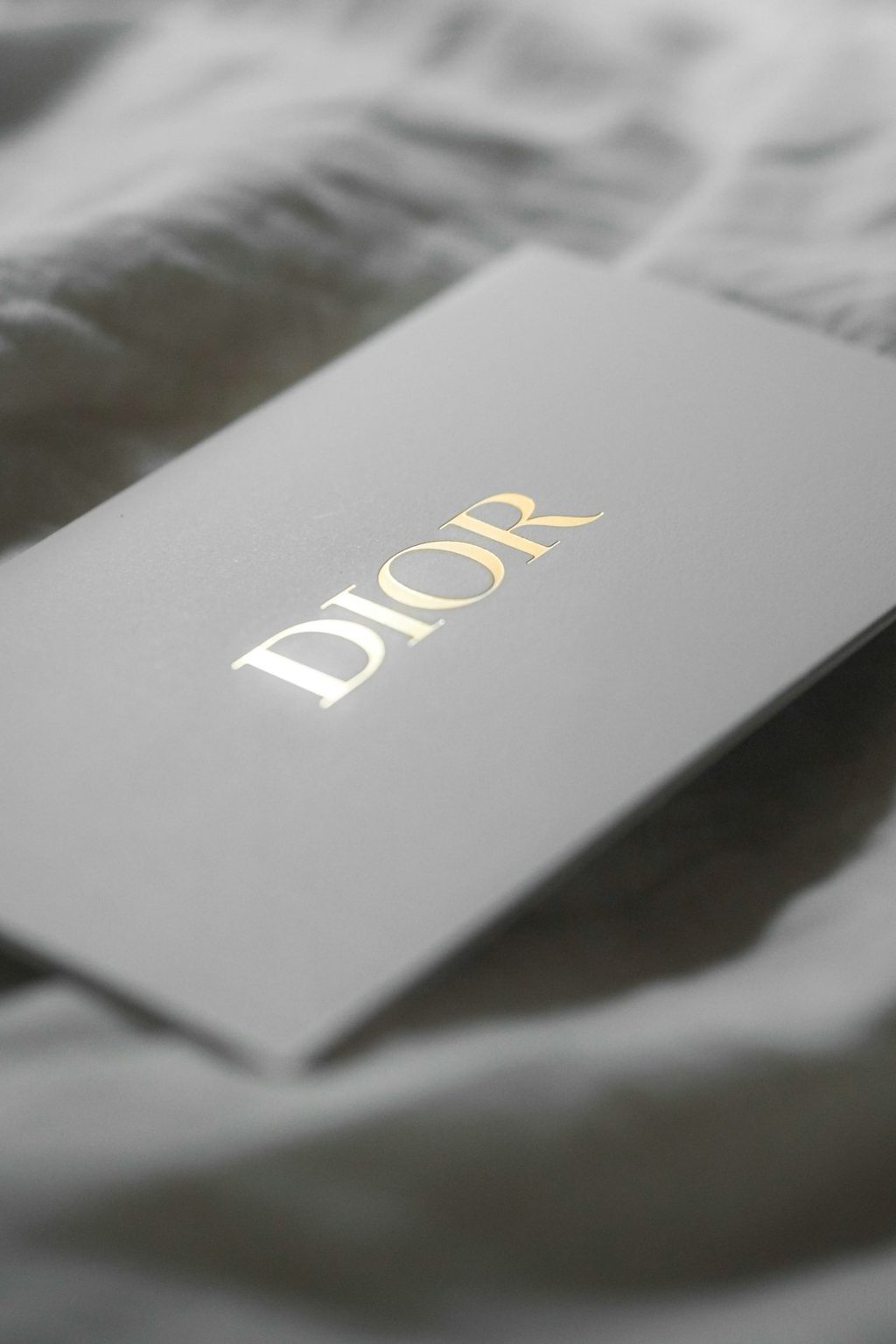 Label mewah dengan logo Dior di atas latar belakang tekstur, menggambarkan pentingnya penempatan QR code pada label kemasan premium