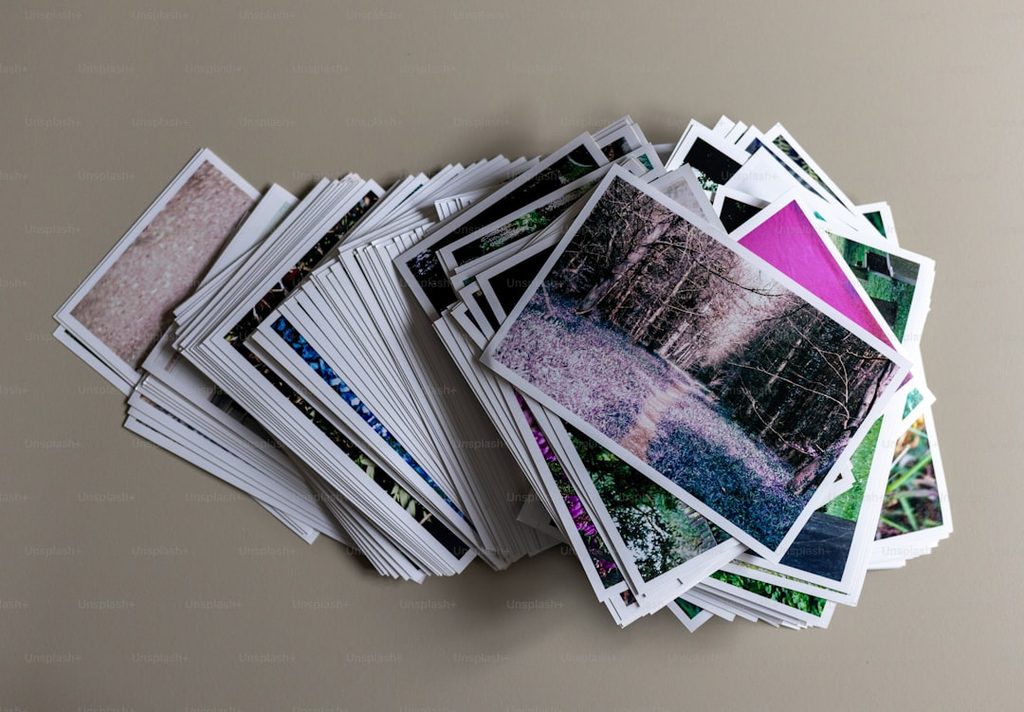Stack of various photos and cards on a beige surface.