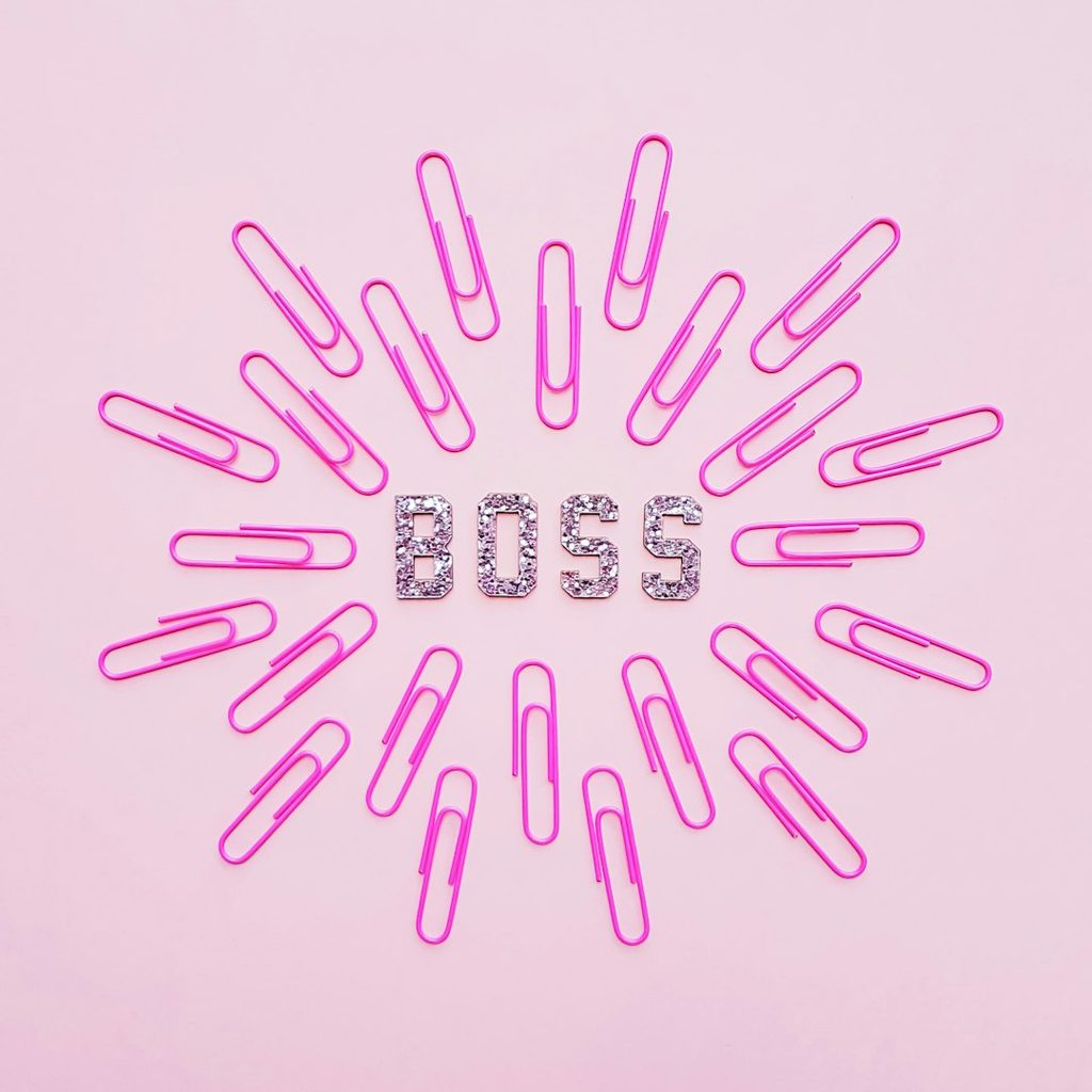 Huruf 'BOSS' dibuat dari klem pink di latar belakang warna pastel.