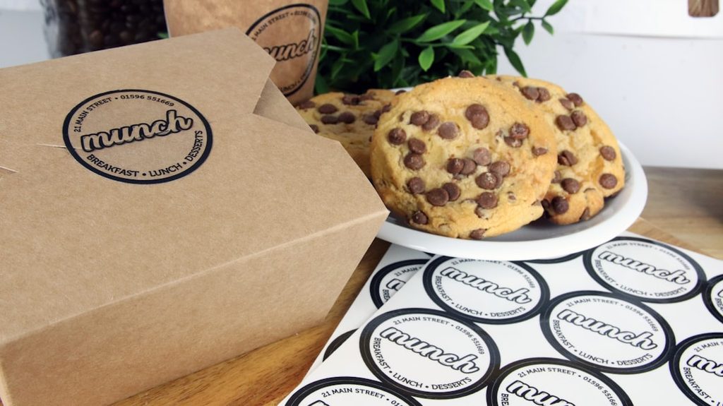 Kemasan kertas kotak dan stiker 'Munch' dengan kue cookies cokelat.