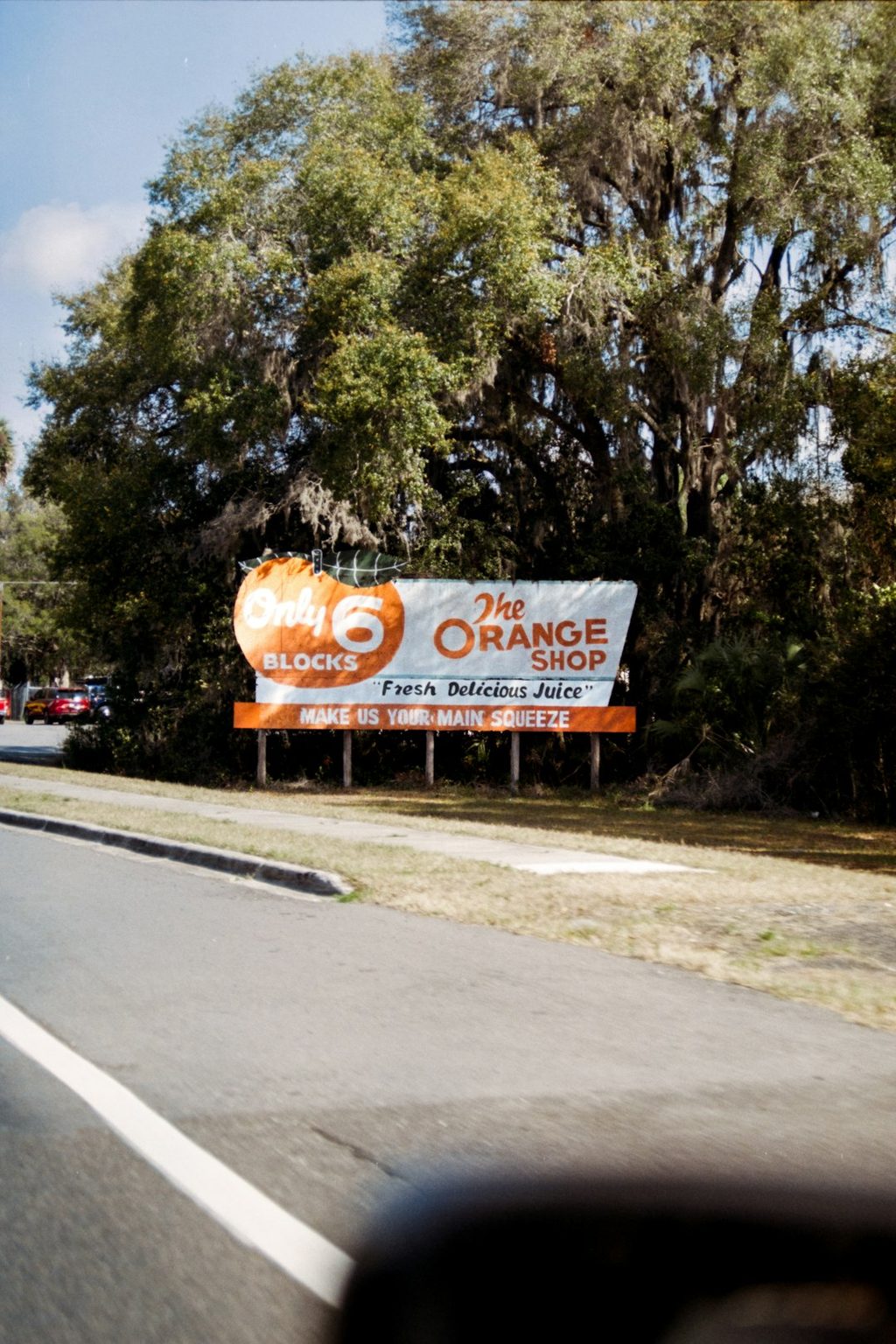 Billboard iklan Orange Shop di pinggir jalan.