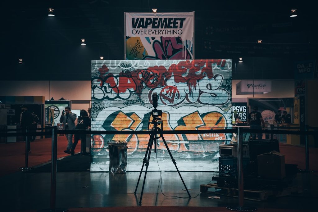 Graffiti besar di pameran Uprint.id dengan banner Vape Meet Over Everything.