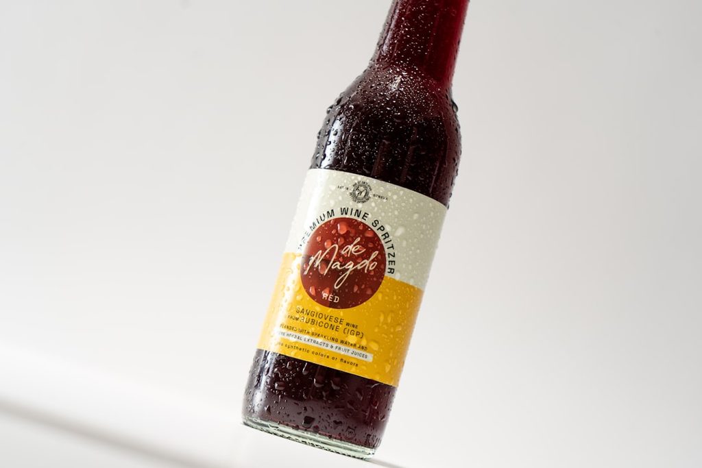 Botol minuman dengan label merah dan kuning, tampak dari sisi depan.