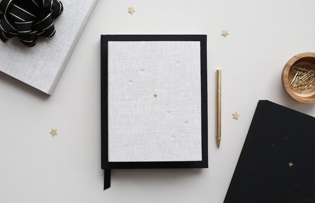 Notebook putih dengan tampilan bersih yang menggambarkan pentingnya white space dan tipografi rapi pada materi cetak