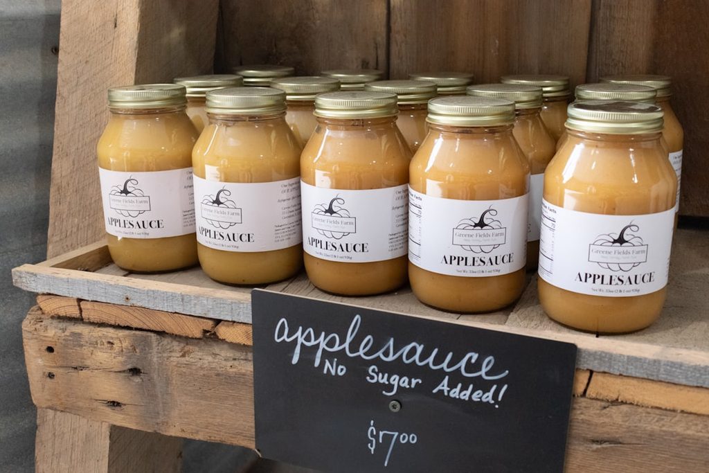 Botol-botol Applesauce tanpa gula ditampilkan di rak kayu.