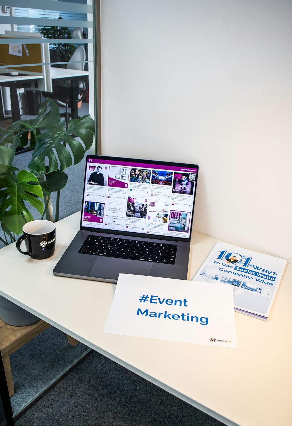 Laptop dengan banner Event Marketing dan brosur di meja.