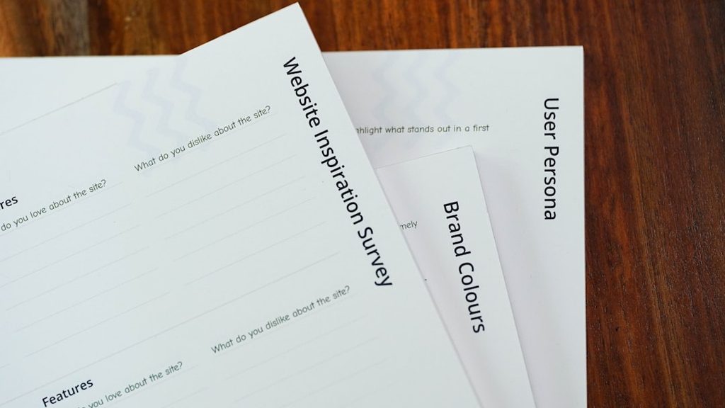 Tiga lembaran kertas dengan judul Website Inspiration Survey, Brand Colours, dan User Persona.
