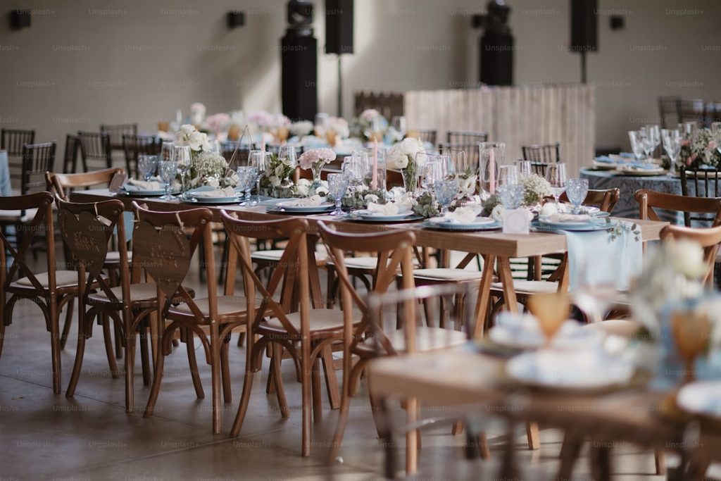 Meja makan elegan dengan dekorasi bunga dan piring mewah di ruang besar sebagai inspirasi penataan meja bridal shower.