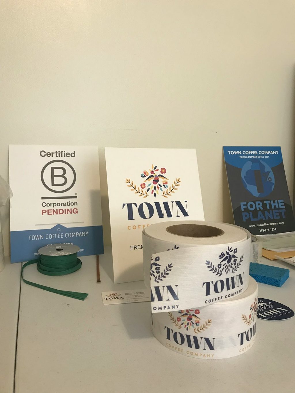 Gambar menunjukkan produk percetakan TOWN Coffee Company termasuk kertas, stiker, dan logo.
