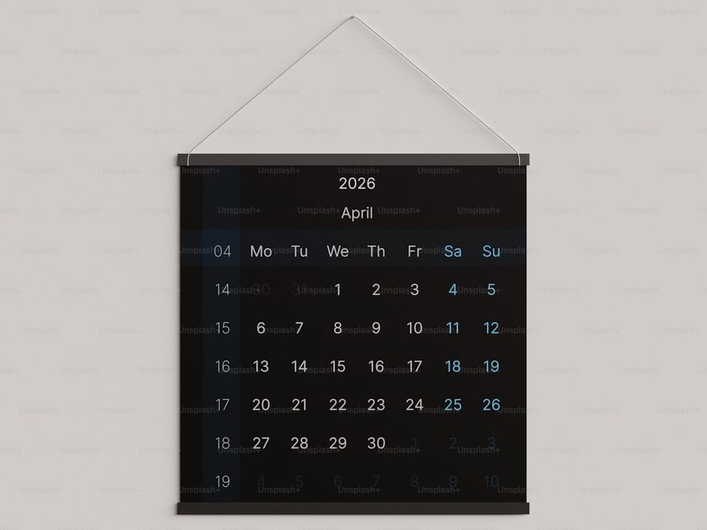 Kalender April 2026 dengan warna hitam dan putih di dinding.