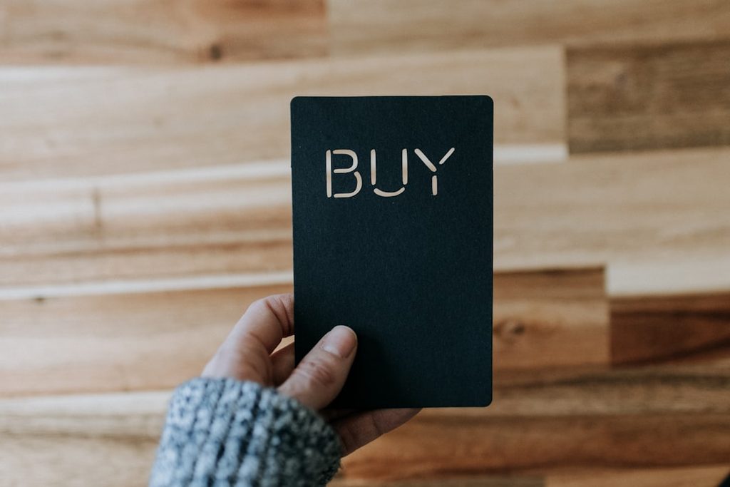 a person holding a black book with the word buy written on it for decision stage concept
