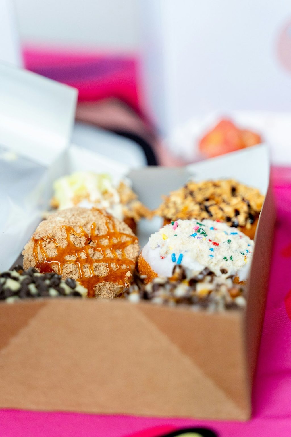 Kue kecil berbagai rasa dalam kotak kertas, ideal untuk kado atau snack ringan.