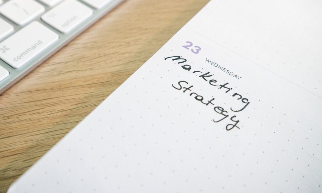 a notepad with the words marketing strategy written on it untuk evaluasi vendor dan produksi cetak