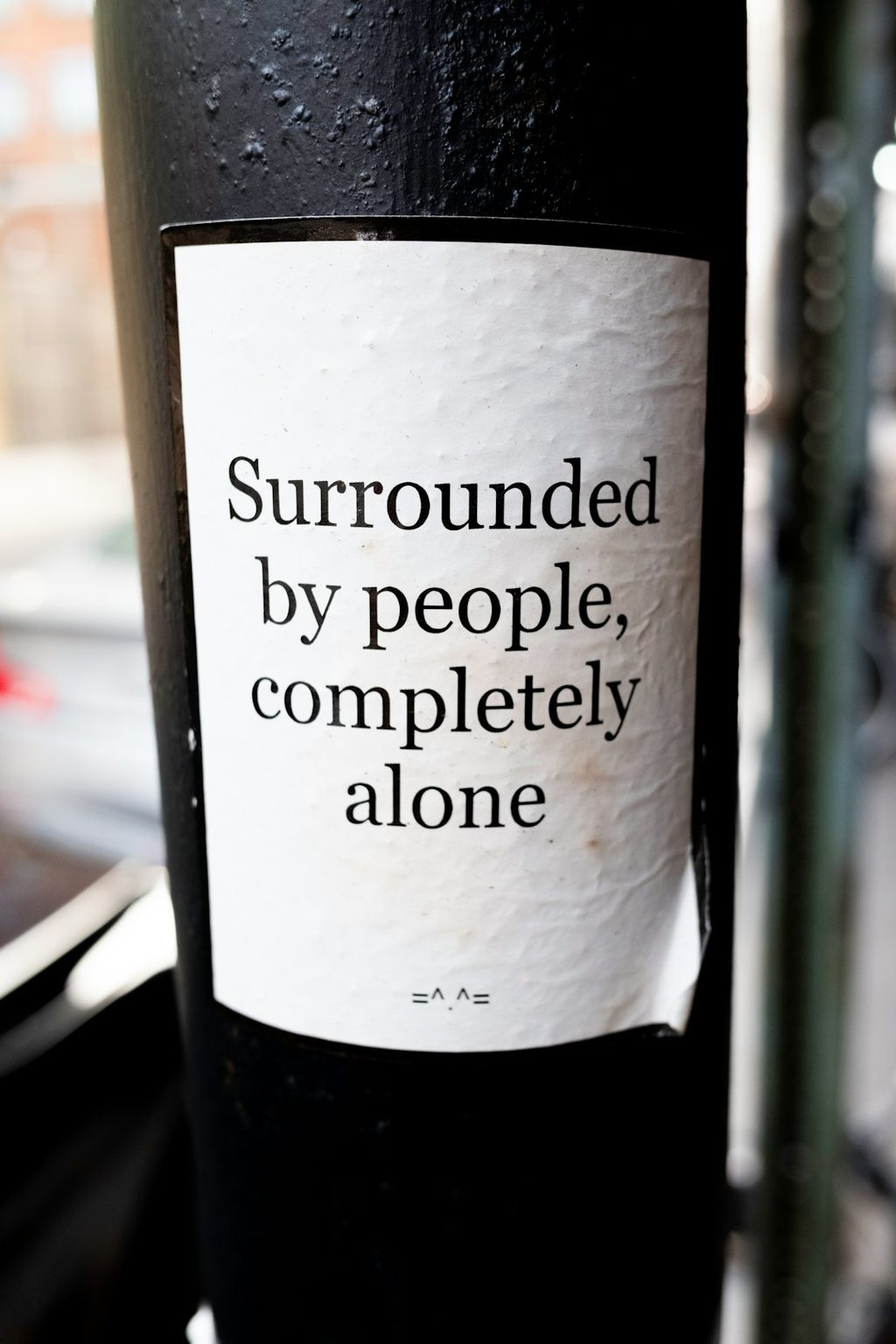 Label dengan pesan 'Surrounded by people, completely alone' dan simbol tersenyum