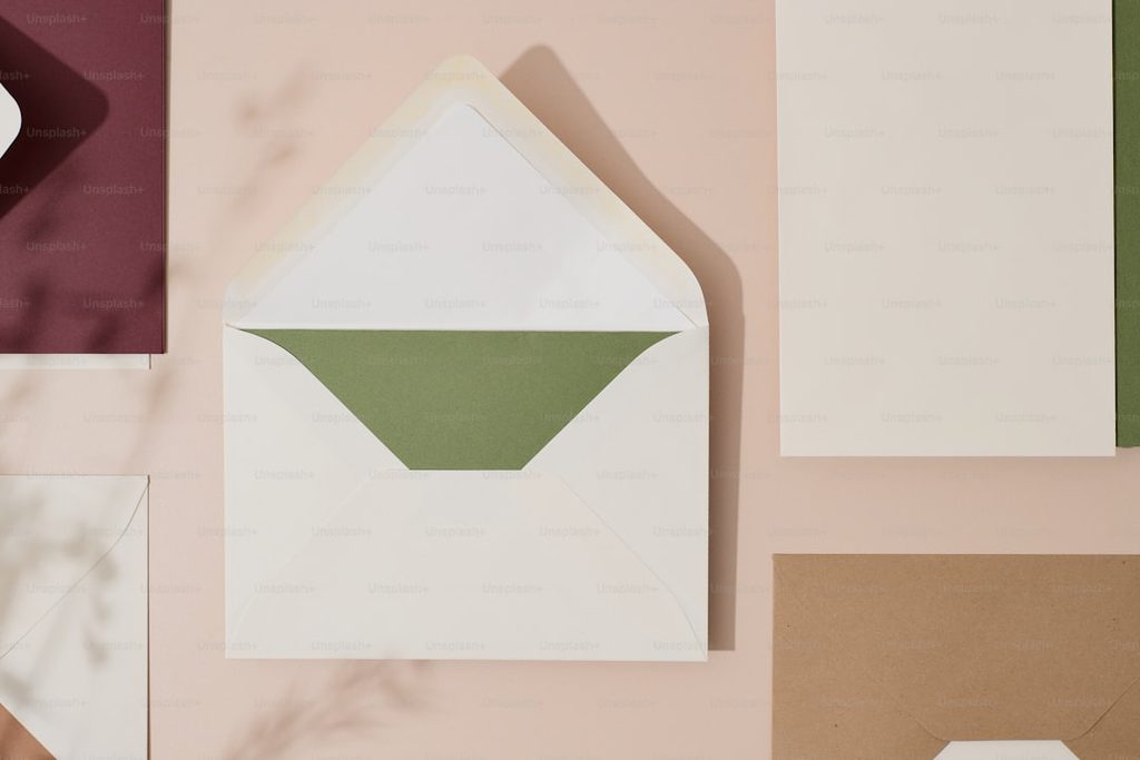 Close-up of white envelopes with green inserts on a pastel background.