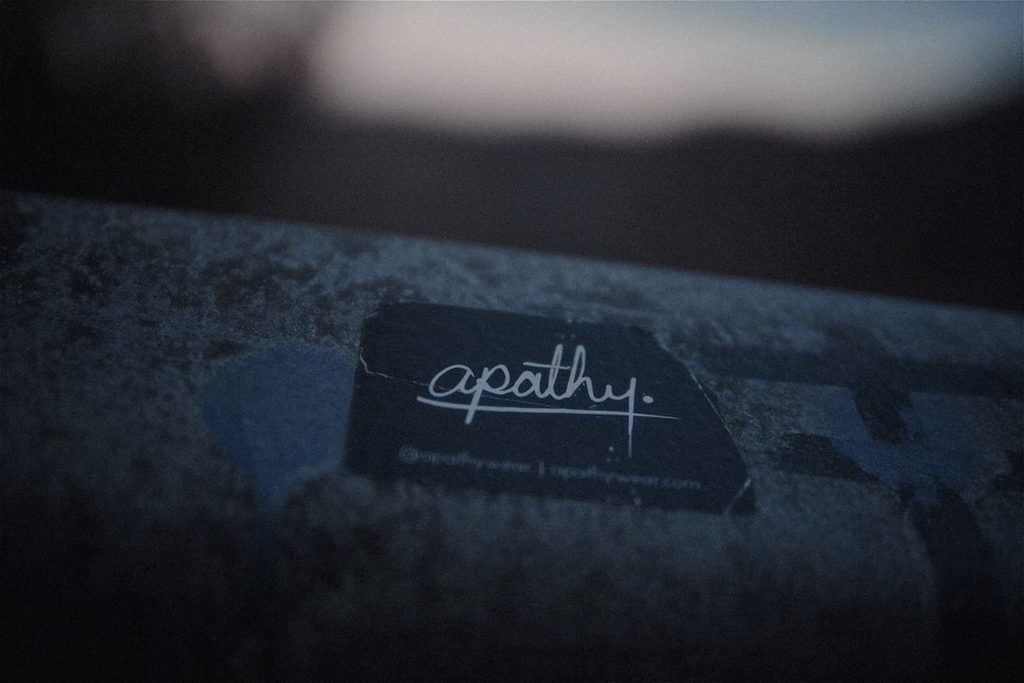 Label hitam dengan logo Apathy di atas permukaan tekstur.