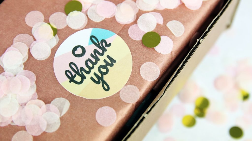 Stiker 'thank you' dengan pola warna cerah di kemasan produk.