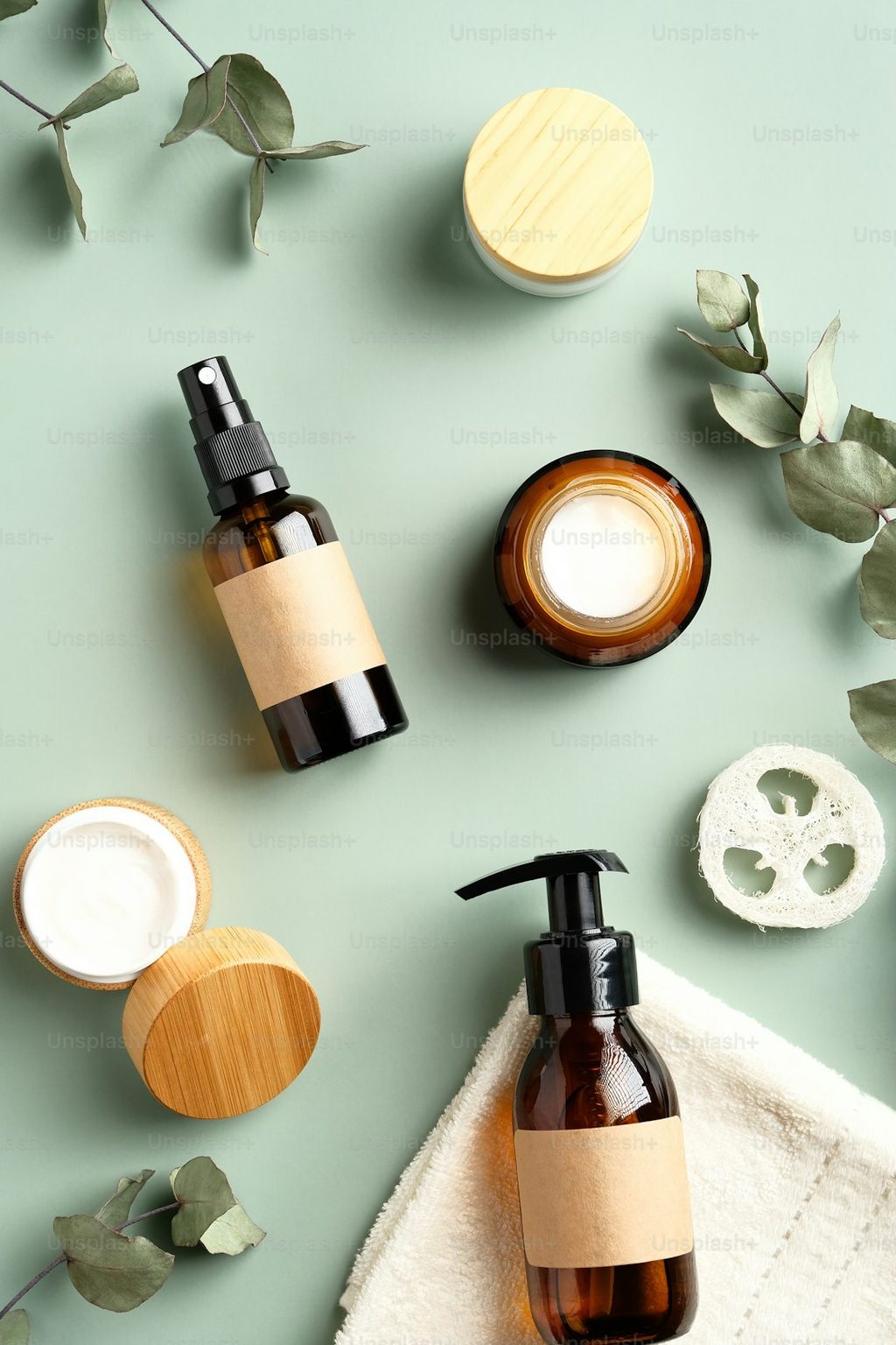 Kemasan kosmetik dengan botol dan kemasan bambu di meja hijau.